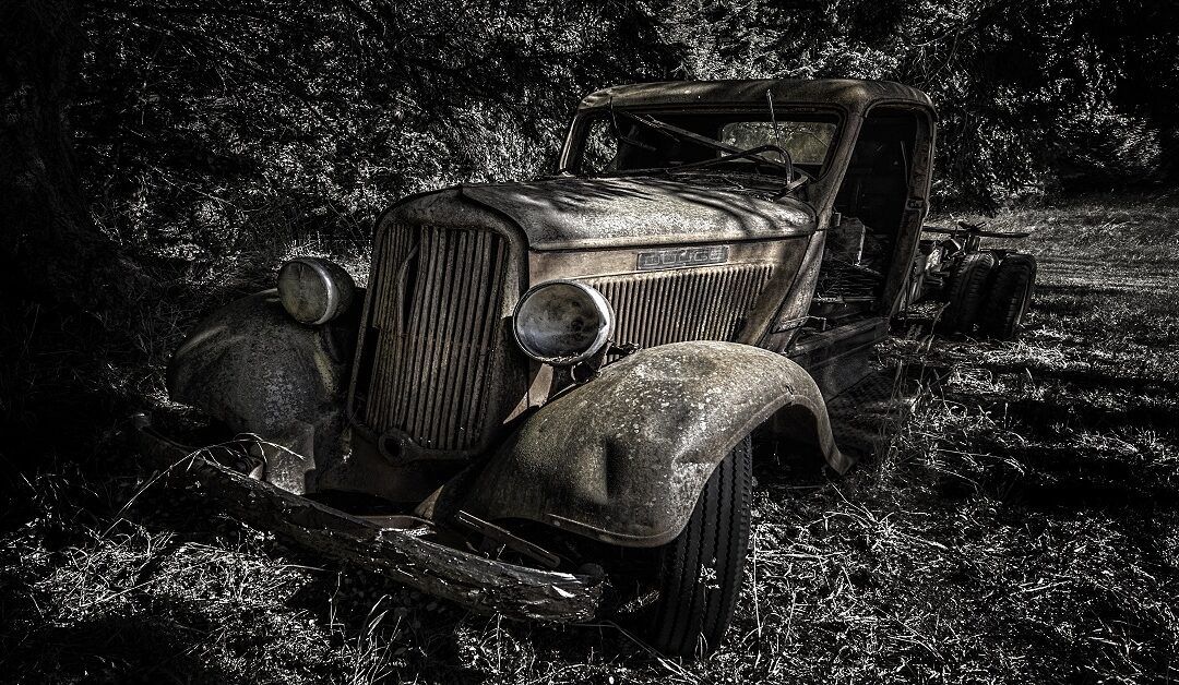 Greyscale Shot Of An Old Retro Car In The Forest During Daytime